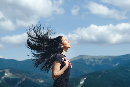 Long hair brunette girl on the top of the mountain with streaming hairの写真素材