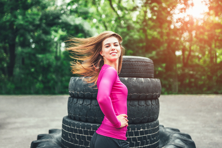 Sporty girl near huge old tires outdoorの写真素材
