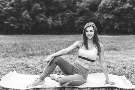 Pretty sporty girl showing stretching exercises outdoor, black and whiteの写真素材