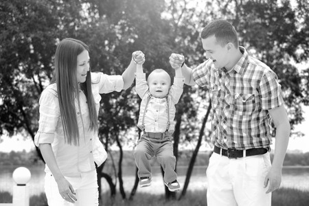 Young happy parents playing with little son outdoor in the parkの写真素材