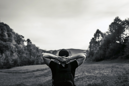 Young tourist man in the mountains with sky and forest on background, black and whiteの写真素材