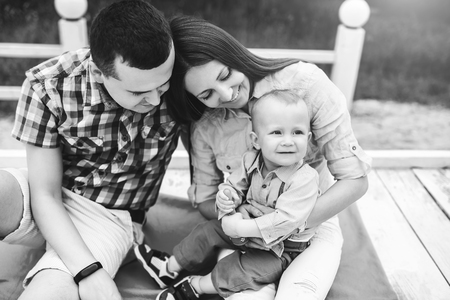 Young happy parents playing with little son outdoor in the park, black and whiteの写真素材