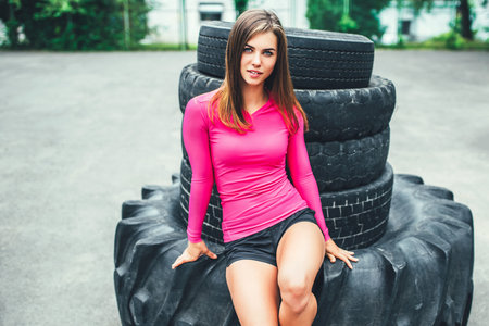 Sporty girl near huge old tires outdoor