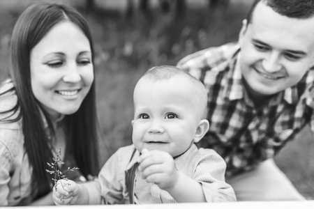 Young happy parents playing with little son outdoor in the park, black and whiteの写真素材