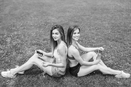 Two pretty sporty girls relaxing after workout outdoor, black and whiteの写真素材