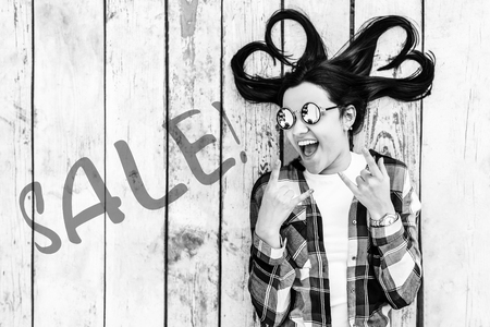 Girl on wooden background with ''sale'' word on it, black and whiteの写真素材