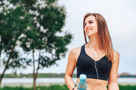 Pretty sporty girl with phone and bottle outdoorの写真素材