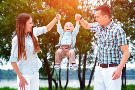 Young happy parents playing with little son outdoor in the parkの写真素材