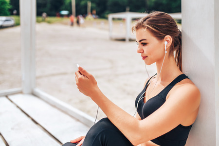 Pretty sporty girl with phone and bottle outdoorの写真素材