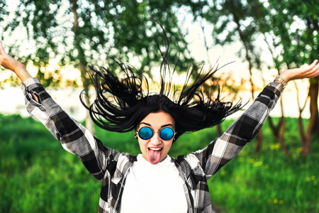 Happy pretty girl outdoor showing tongue and throw her hairの写真素材
