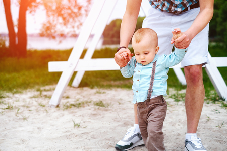Young father with his little son have fun and learning to walk outdoor in the parkの写真素材