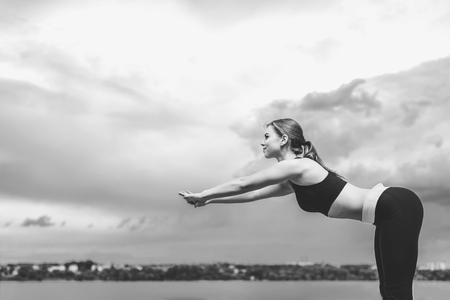 Pretty sporty girl showing stretching exercises outdoor, black and whiteの写真素材