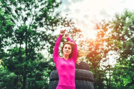Sporty girl near huge old tires outdoorの写真素材
