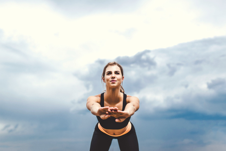 Pretty sporty girl showing stretching exercises outdoorの写真素材