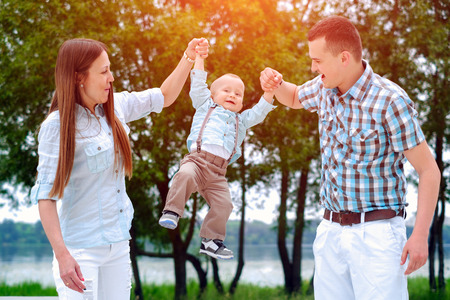 Young happy parents playing with little son outdoor in the parkの写真素材