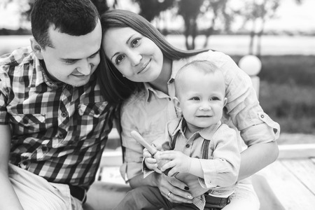 Young happy parents playing with little son outdoor in the park, black and whiteの写真素材