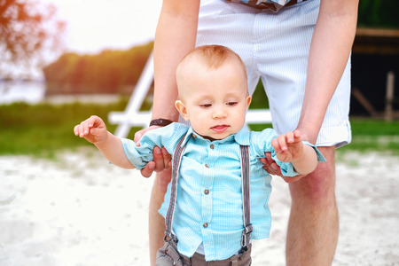 Young father with his little son have fun and learning to walk outdoor in the parkの写真素材