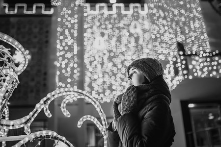 Girl outdoor in cold weather with christmas lights behindの写真素材