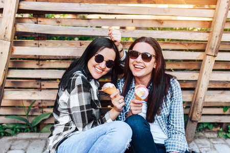 Two pretty brunette girls with ice cream outdoorの写真素材