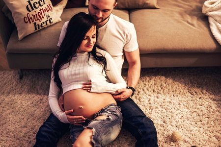 Pregnant mother and her husband at home with christmas decorationsの写真素材