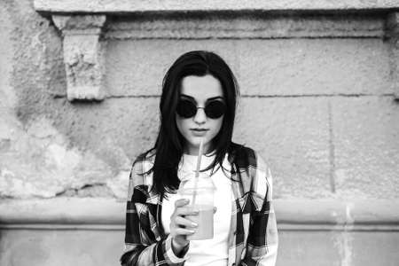 Pretty brunette girl drinking cold coffee outdoor, black and whiteの写真素材