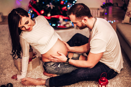 Pregnant mother and her husband at home with christmas decorationsの写真素材
