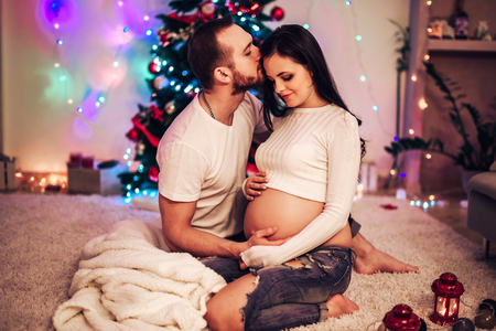 Pregnant mother and her husband at home with christmas decorationsの写真素材