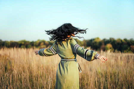 Pretty brunette girl in long embroidery dress outdoorの写真素材