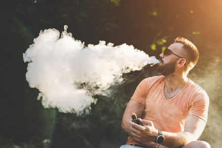 Vaper with beard with electronic cigarette outdoorの写真素材