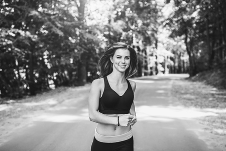 Sporty young fitness girl running and listening music in the park, black and whiteの写真素材
