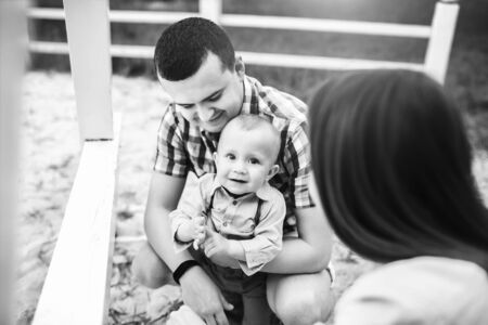 Young happy parents playing with little son outdoor in the park, black and whiteの写真素材