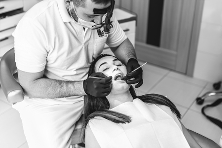 Dentist working in dental clinic with patient in the chair, black and whiteの写真素材