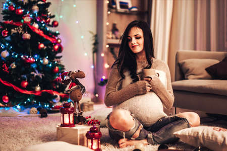Happy pregnant women at home with christmas decorations の写真素材