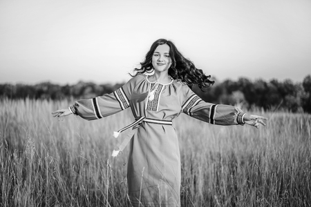 Pretty brunette girl in long embroidery dress outdoorの写真素材