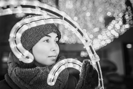 Girl outdoor in cold weather with christmas lights behindの写真素材
