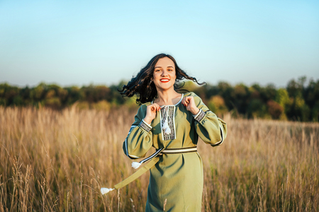 Pretty brunette girl in long embroidery dress outdoorの写真素材