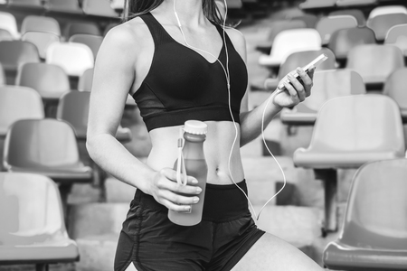 Pretty sporty girl with phone and bottle outdoor, black and whiteの写真素材