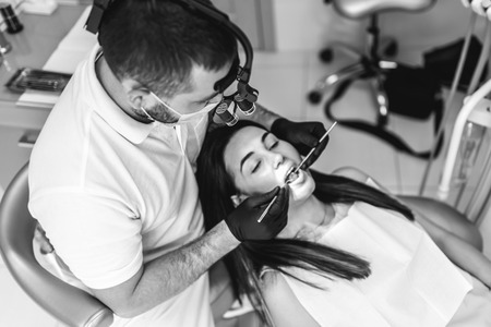 Dentist working in dental clinic with patient in the chair, black and whiteの写真素材