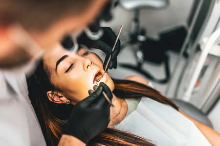 Dentist working in dental clinic with patient in the chairの写真素材