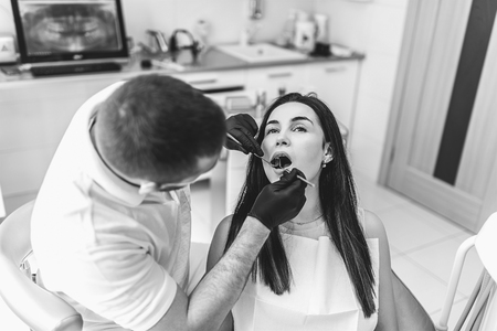 Dentist working in dental clinic with patient in the chair, black and whiteの写真素材