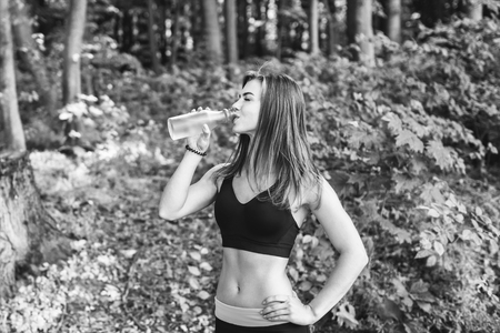 Sporty young fitness girl drinking water in the park, black and whiteの写真素材