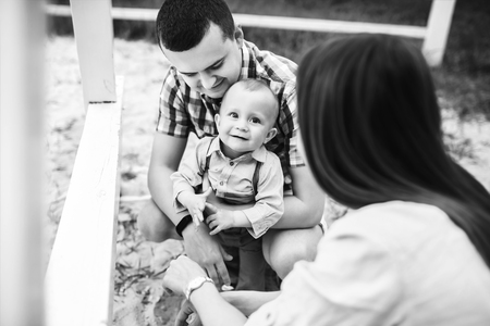 Young happy parents playing with little son outdoor in the park, black and whiteの写真素材