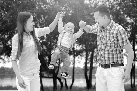 Young happy parents playing with little son outdoor in the parkの写真素材