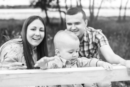 Young happy parents playing with little son outdoor in the park, black and whiteの写真素材