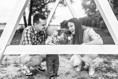 Young happy parents playing with little son outdoor in the park, black and whiteの写真素材
