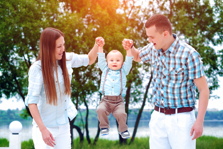 Young happy parents playing with little son outdoor in the parkの写真素材