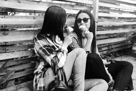 Two pretty brunette girls with ice cream outdoorの写真素材