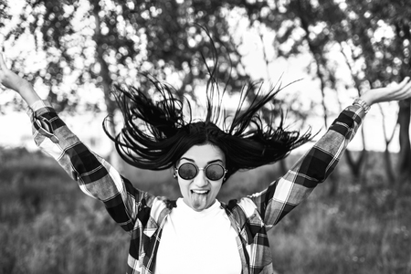 Happy pretty girl outdoor showing tongue and throw her hair, black and whiteの写真素材