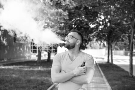Vaper with beard with electronic cigarette outdoorの写真素材