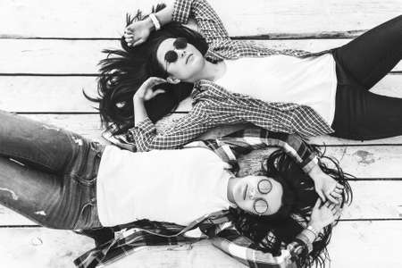 Two pretty brunette girls relaxing on wooden backgroundの写真素材